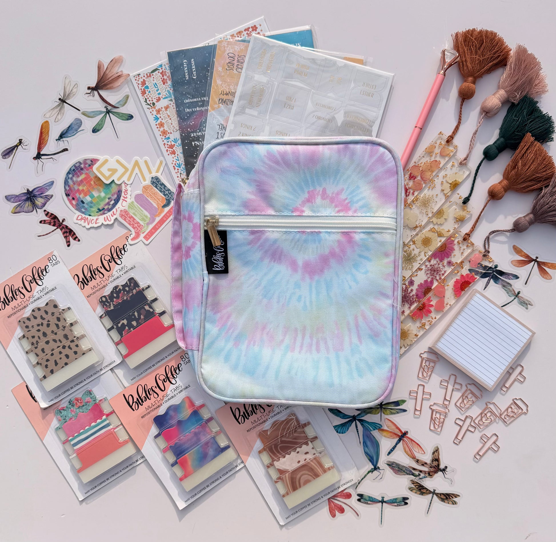 Tie-dye pouch surrounded by stationery items on a light background