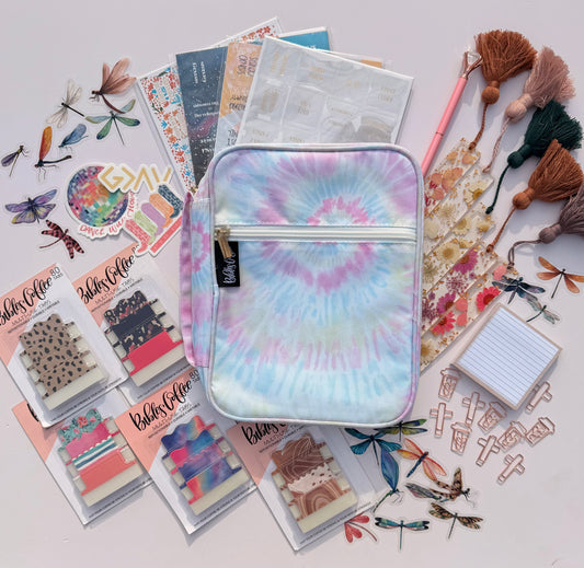 Tie-dye pouch surrounded by stationery items on a light background